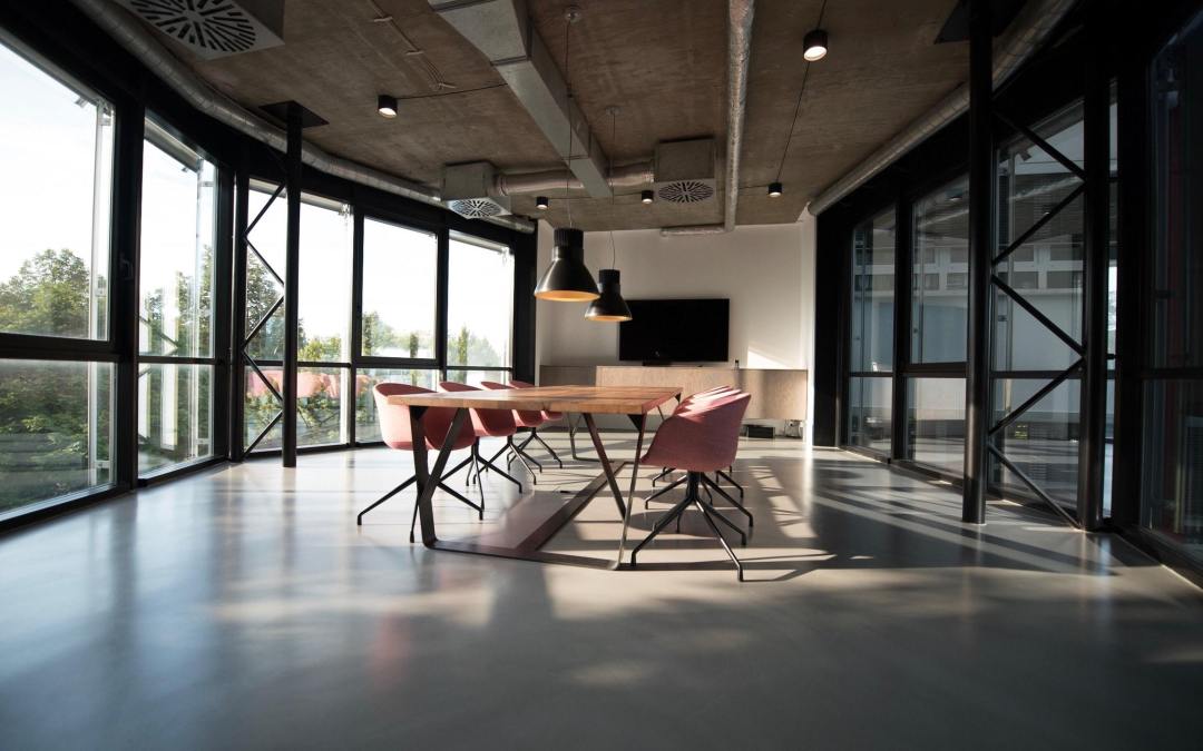 A large living room with harsh sunlight coming through the wall of windows.