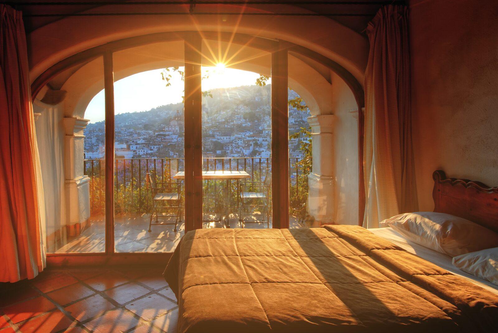 Sunset view of bedroom with arch windows and a bed
